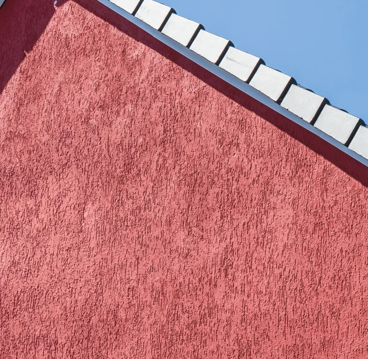 Red textured façade finish under a blue sky