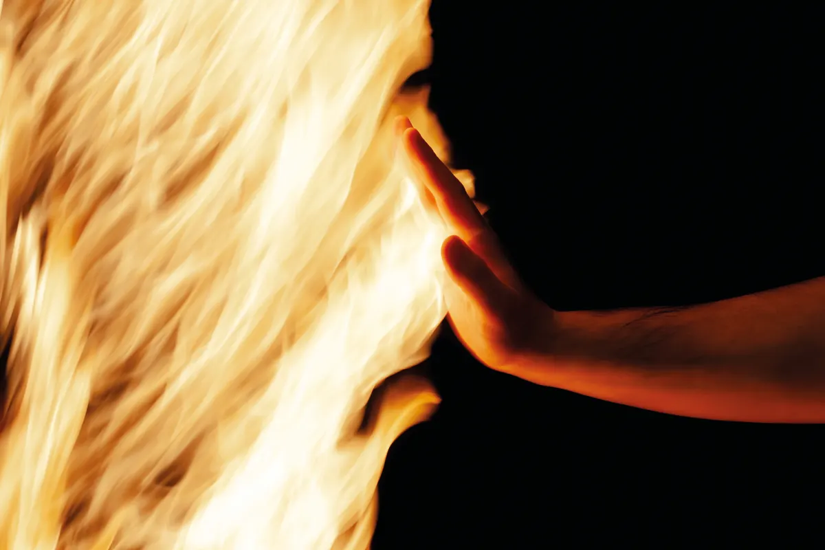 A hand held up against a wall of flames