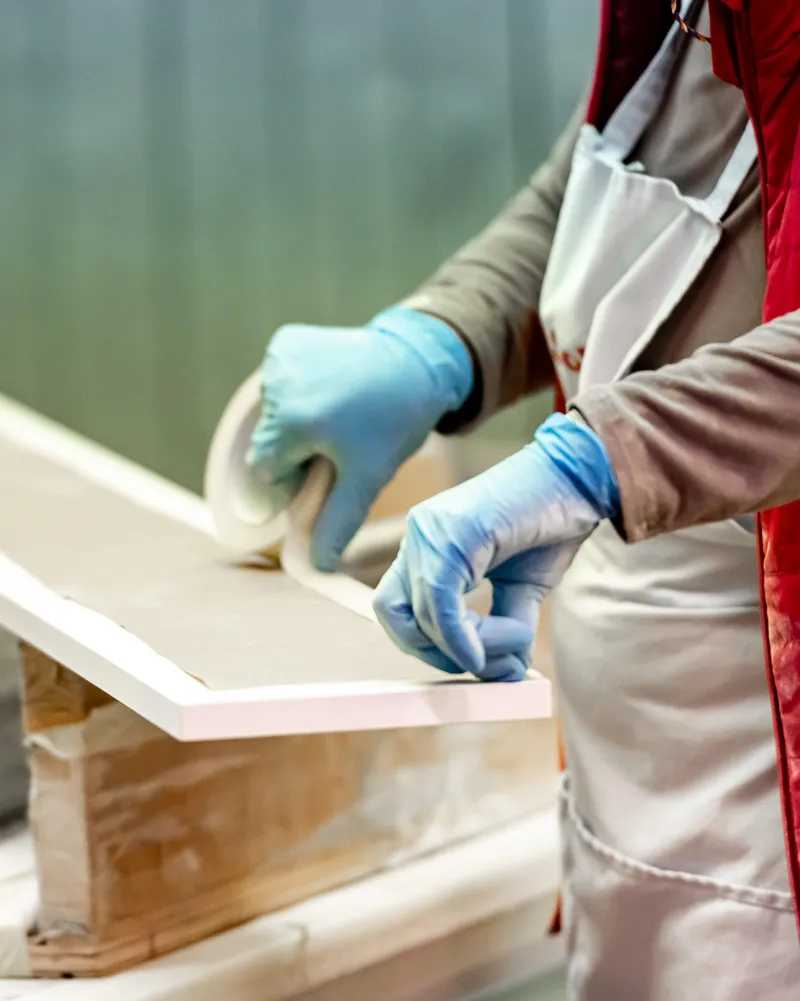 Gloved hands finishing the edge of a wood panel
