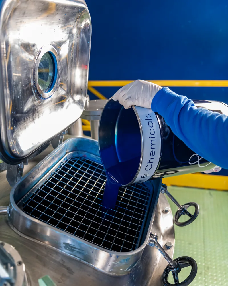 Blue coating poured from a DAAS & Chemicals can into a stainless-steel mixer at the Fontanafredda plant